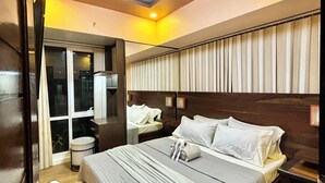 Una habitación de hotel con una cama grande, una mesita de noche, una ventana con cortinas y una lámpara en el techo.