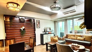 Una sala de estar moderna con comedor, pared de paneles de madera y un ventanal grande.