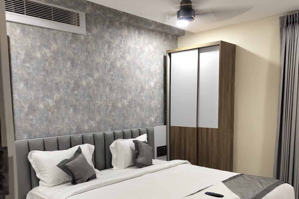 Ein modernes Hotelzimmer mit einem großen Bett, einem Deckenventilator, einem Kleiderschrank und einem Fenster mit Vorhängen.