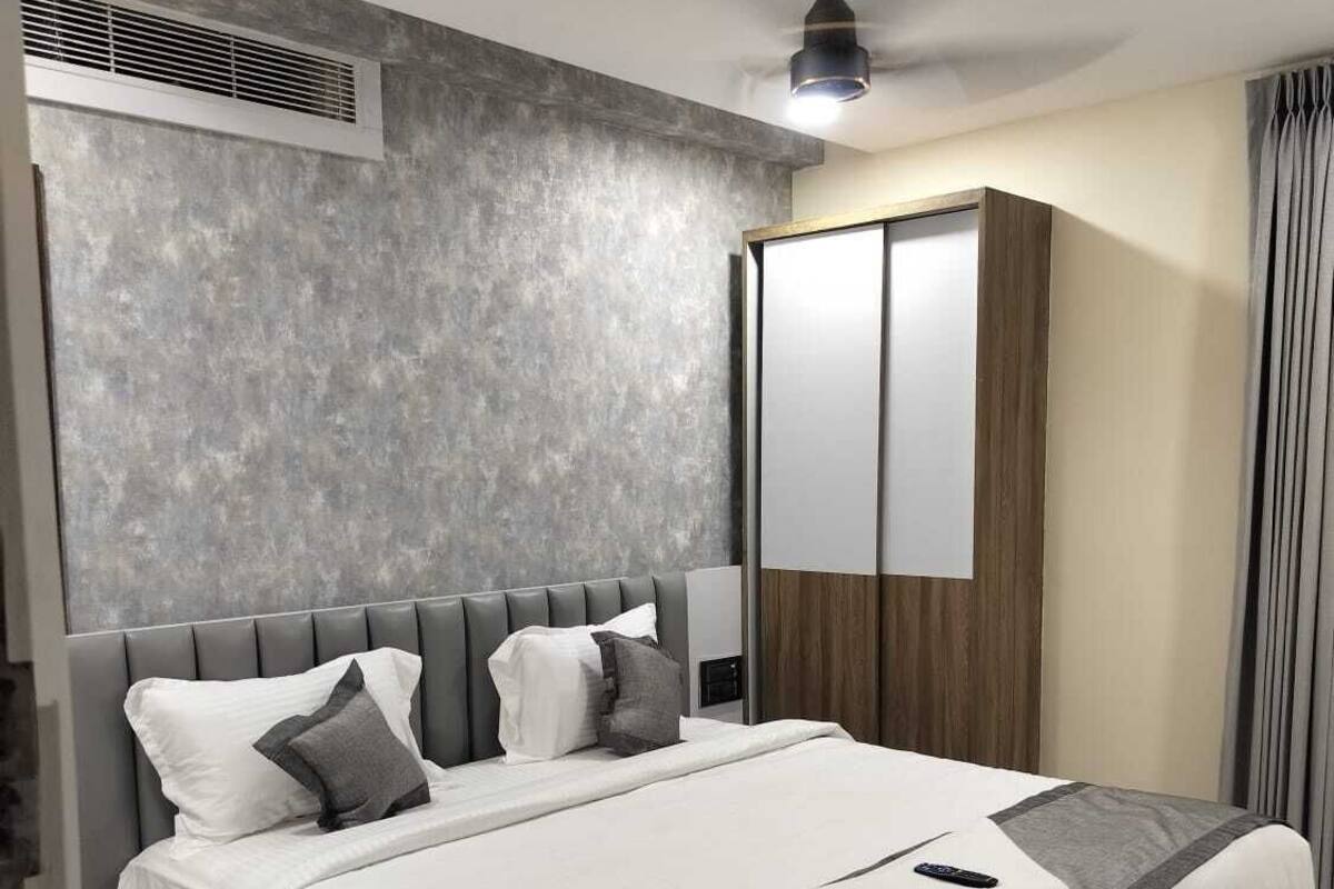 A modern hotel room with a large bed, a ceiling fan, a wardrobe, and a window with curtains.