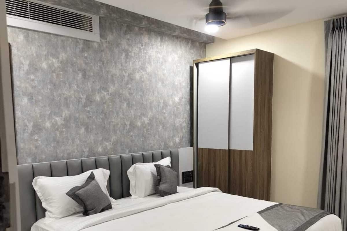 Une chambre d’hôtel moderne dotée d’un grand lit, d’un ventilateur de plafond, d’une armoire et d’une fenêtre avec des rideaux.