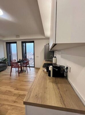 Eine moderne Küche mit Holzarbeitsplatte, ein Essbereich mit roten Stühlen und Blick durch Glastüren.