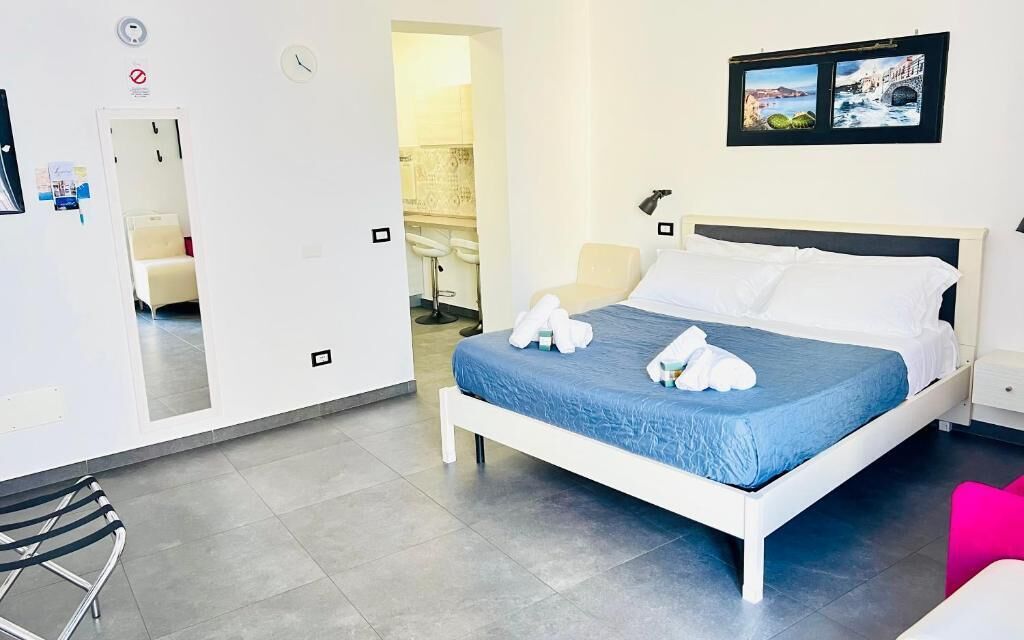 A hotel room with a bed, a chair, a desk, and a bathroom visible through an open door.