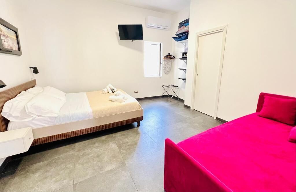 A bedroom with a bed, a red chair, a TV, and a wardrobe.