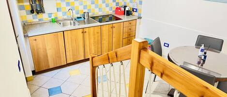 Una cocina con gabinetes de madera, salpicadero de azulejos y comedor con mesa y sillas.