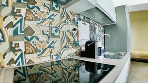 Eine Küche mit einem gemusterten Rückwand, einer Kaffeemaschine und einer modernen Arbeitsplatte.