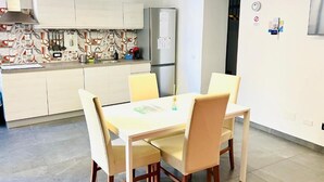 Eine moderne Küche mit Esstisch und Stühlen, einem Kühlschrank und einer gefliesten Spritzschutzwand.