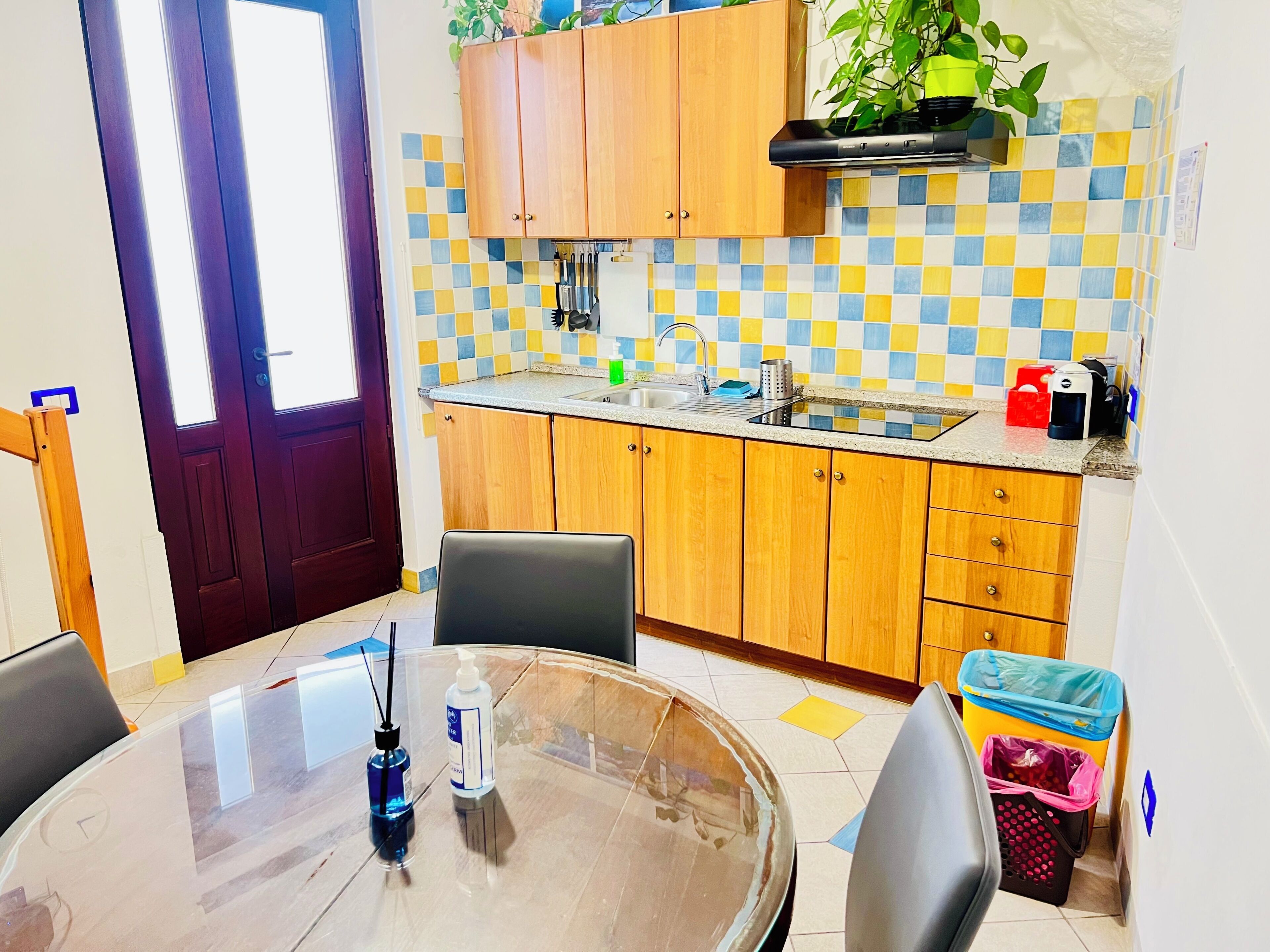 Una cocina con armarios de madera, salpicadero de azulejos, un lavamanos y una mesa de comedor con sillas.