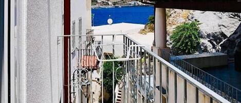 Un balcon donnant sur la mer, un mur de pierre et un bâtiment avec un toit rouge.