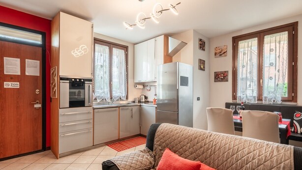 Une cuisine compacte dotée d’appareils électroménagers modernes, un coin repas avec une table et des chaises, et un espace salon confortable avec un canapé.