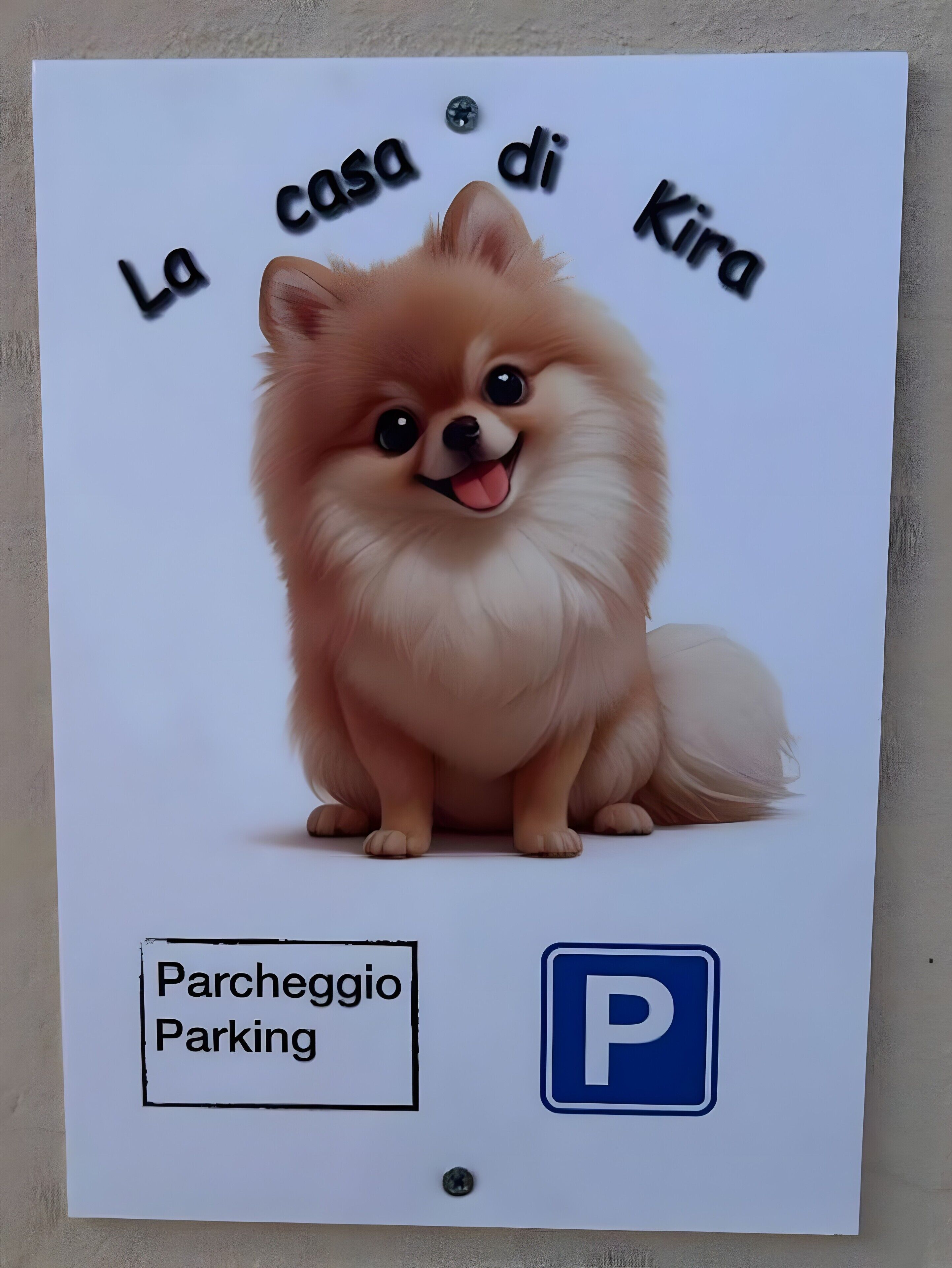 Un panneau représentant un chien de race spitz nain, avec l’inscription « La casa di Kira » et un symbole indiquant un espace de stationnement.