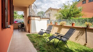 Une terrasse couverte avec deux chaises longues, une table et un escalier menant à un niveau supérieur.
