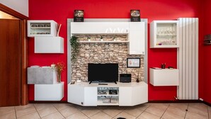 Un salon avec un mur en pierre, un téléviseur à écran plat et des meubles de rangement blancs.