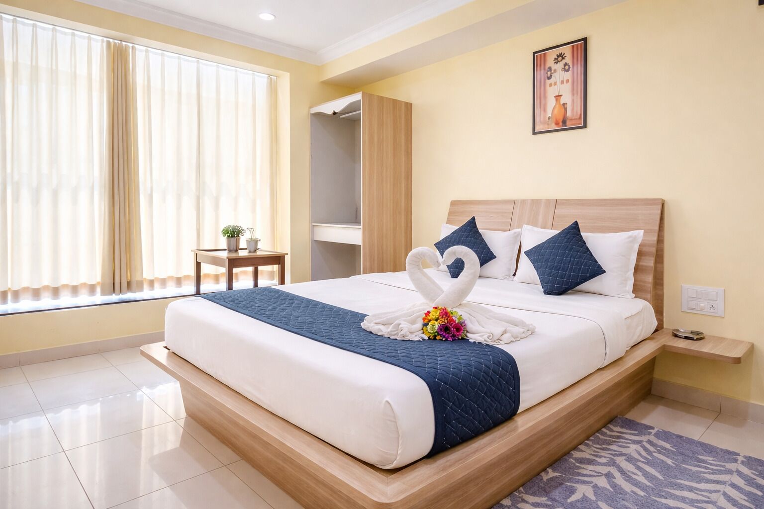 A hotel room with a bed, a bedside table, a nightstand, a window with curtains, and a painting on the wall.