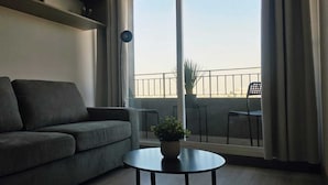 En moderne stue med sofa, et lille bord og en balkon med stole.