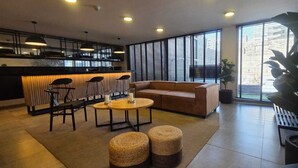 Et moderne interiør med et køkkenområde, siddepladser og store vinduer.