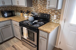 Una cocina con estufa negra, microondas y salpicadero de azulejos.
