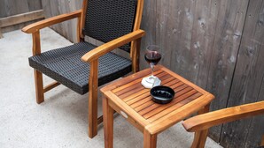 Ein Holz-Stuhlgarnitur und Tisch im Freien, mit einem Glas Rotwein.