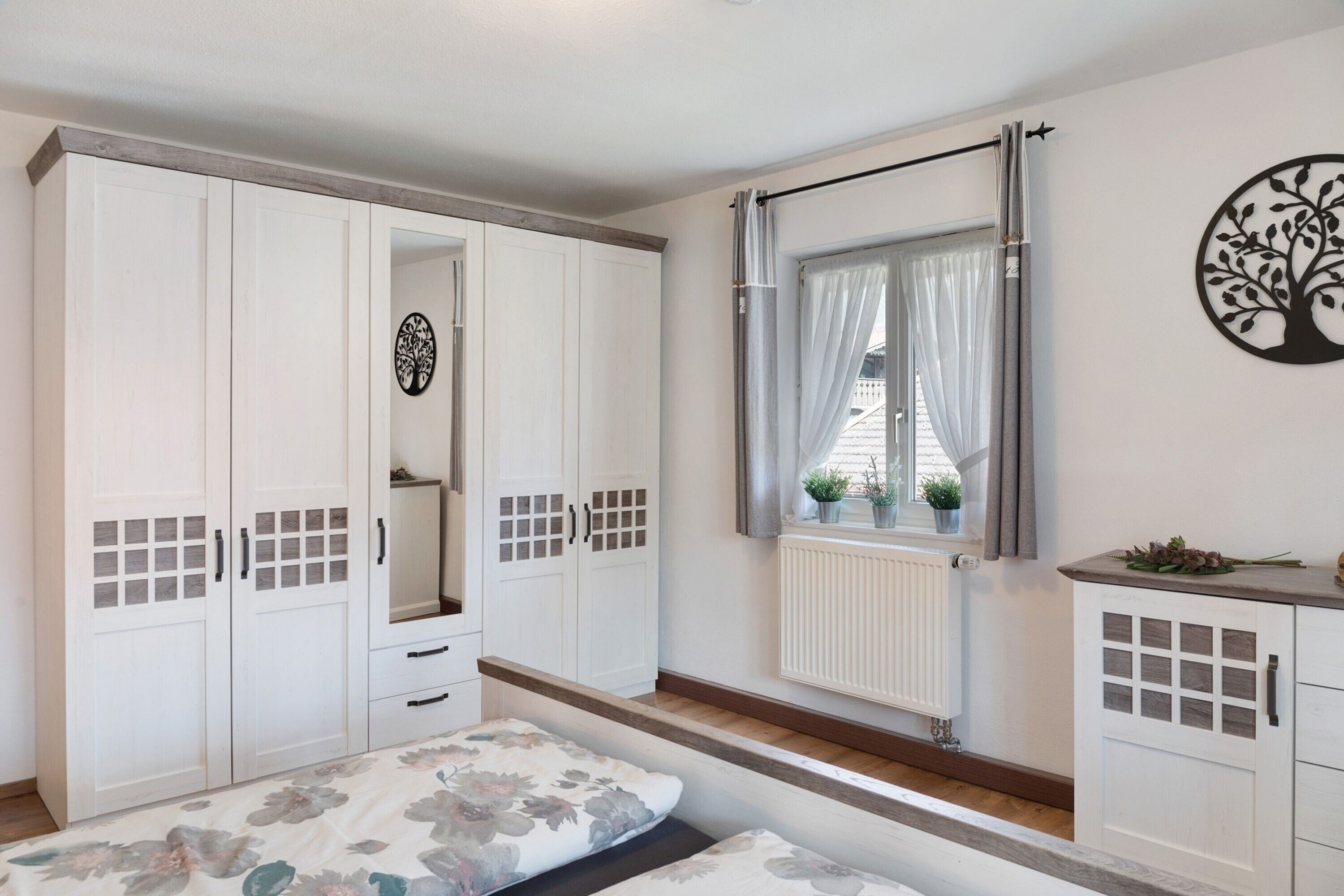 A bedroom with a bed, wardrobe, and window with curtains.