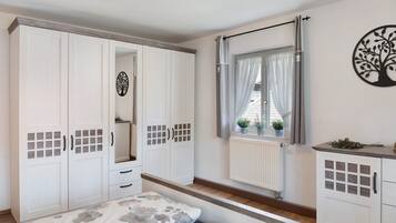 A bedroom with a bed, wardrobe, and window with curtains.