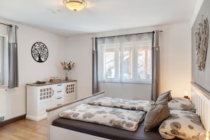 A bedroom with a bed, a dresser, a window with curtains, and a wall decoration. - Apartment 'Andis' with Mountain View, Balcony and Wi-Fi (Farchant)