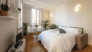 A modern bedroom with a bed, bedside table, chair, and potted plants. - Exclusive suite with Cathedral view | Elegant design in the heart of Ferrara (Ferrara)