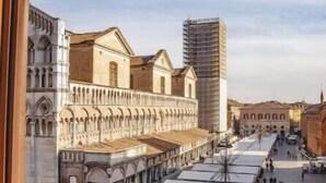 A view from a window overlooking a street with historic buildings and a modern skyscraper. - Exclusive suite with Cathedral view | Elegant design in the heart of Ferrara (Ferrara)