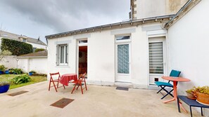 Eine kleine Terrasse mit Tisch und Stühlen, einer Tür und einem Fenster mit Buntglas.