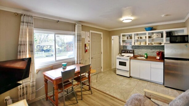 A compact kitchen with white cabinets, a stove, a microwave, and a refrigerator.