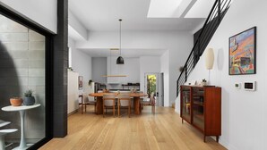 A modern interior with a dining area, kitchen, staircase, and a large window. - Alluring Sophistication Meets Mid-Century Chic (Austin)