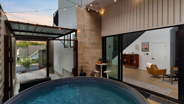 A modern indoor swimming pool with a glass enclosure, a wooden deck, and a view of the outside. - Alluring Sophistication Meets Mid-Century Chic (Austin)