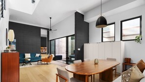 A modern living room with a wooden dining table, sofas, and a large window. - Alluring Sophistication Meets Mid-Century Chic (Austin)