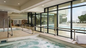 A spa area with a hot tub, a seating area, and large windows offering a view of the outside. - Garden 1 King, Little America, Unwind and Relax, Near Temple Square (Salt Lake City)