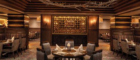 A restaurant with a central round table, multiple seating areas, and a patterned carpet.