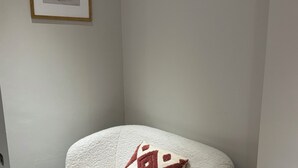 Un sofá de esquina con un cojín estampado, un cuadro enmarcado en la pared y suelo de madera.