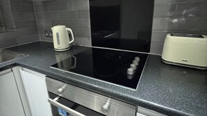 Una cocina con una cocina de inducción negra, un tostador Breville y un hervidor.