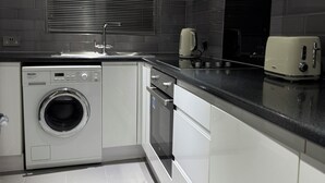 Una cocina moderna con lavadora integrada, un tostador y una ventana con persianas.