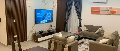 A modern living room with a flat-screen TV, a dining table, sofas, and a coffee table.
