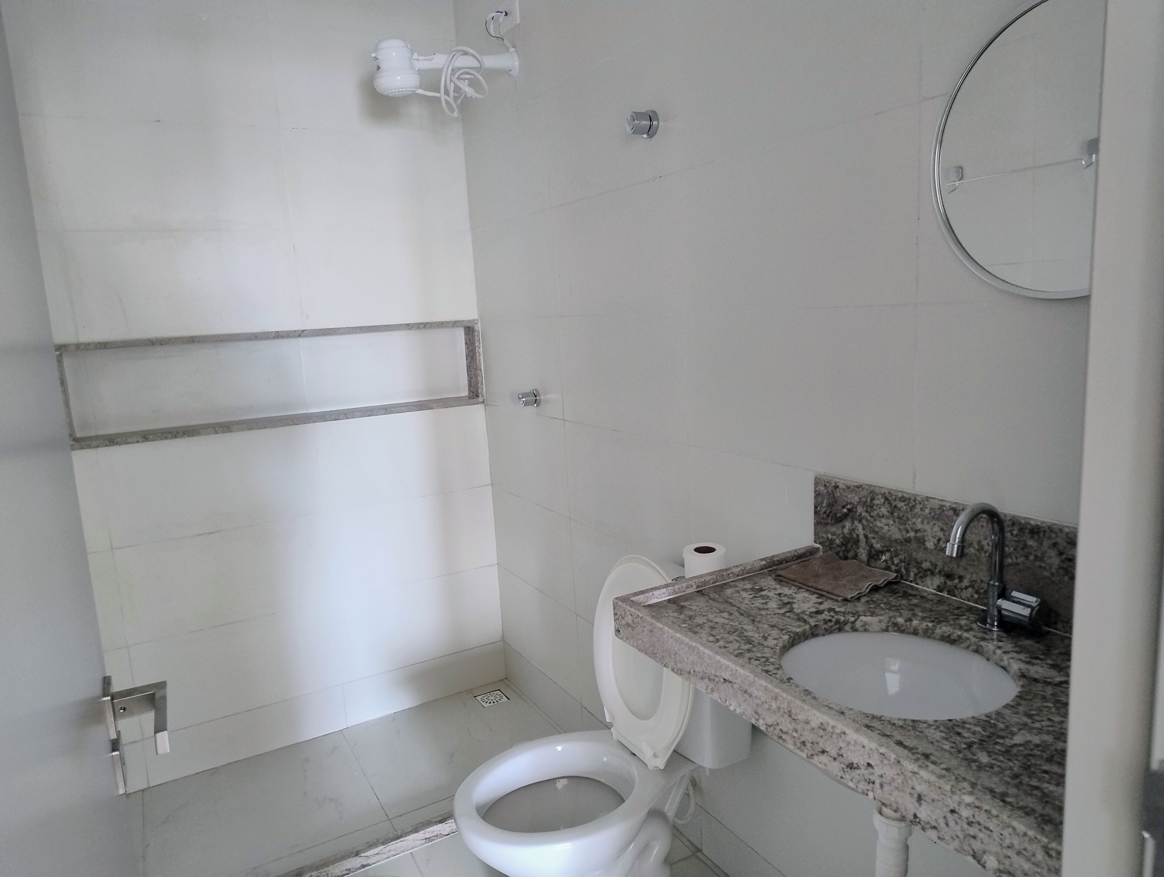 Ein Badezimmer mit Toilette, Waschbecken, Dusche und Handtuchhalter.