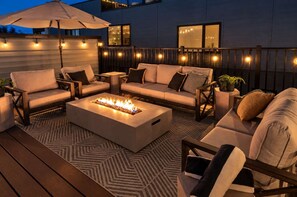 An outdoor seating area with a fire feature, cushioned chairs, and a patterned rug. - Lux 4BR Retreat Rooftop Hot Tub Pool 9 Beds (Nashville)