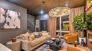 Un salon moderne comprenant un canapé, des fauteuils, une table basse et un lustre.