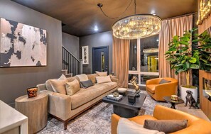 A modern living room with a sofa, armchairs, a coffee table, and a chandelier. - Lux 4BR Retreat Rooftop Hot Tub Pool 9 Beds (Nashville)