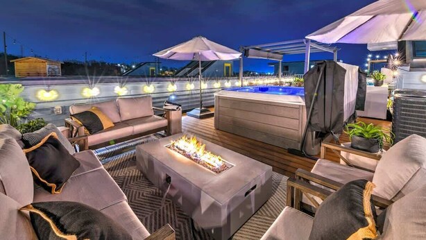 Une terrasse sur le toit dotée d’un jacuzzi, de coins salon extérieurs et d’un éclairage d’ambiance.
