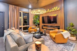 A modern living room with a sofa, armchair, and a coffee table. - Lux 4BR Retreat Rooftop Hot Tub Pool 9 Beds (Nashville)