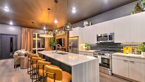 Une cuisine moderne dotée d’un îlot central, de tabourets de bar, d’un four à micro-ondes, d’une cuisinière et d’un réfrigérateur.