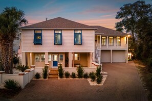 Ein zweistöckiges Haus mit Veranda, Garage und Auffahrt.