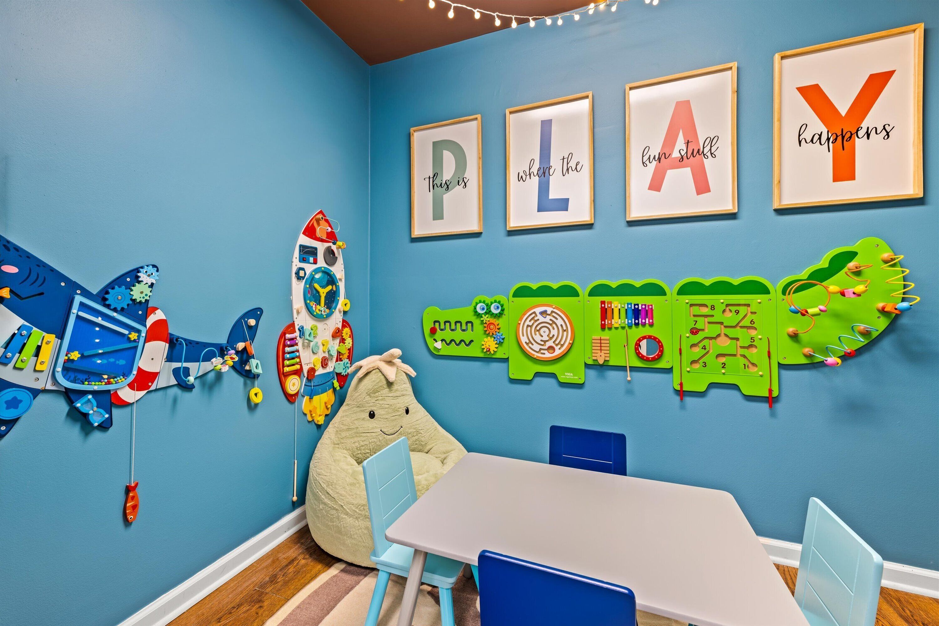 Une salle de jeux pour enfants, équipée de jouets éducatifs, d’une table, de chaises et d’affiches représentant l’alphabet, accrochées au mur.