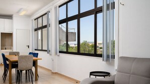 A modern interior with a dining area, sofa, and large windows. - Algarve Townhouse in Loulé by MGM Stays (Loulé)