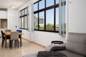 A modern interior with a dining area, sofa, and large windows. - Algarve Townhouse in Loulé by MGM Stays (Loulé)