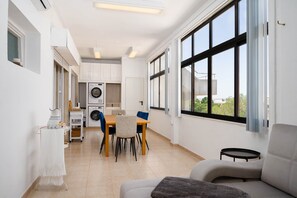 A modern kitchen with a dining area, large windows, and a laundry room. - Algarve Townhouse in Loulé by MGM Stays (Loulé)